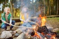 Cute young sisters roasting hotdogs on sticks at bonfire. Children having fun at camp fire. Camping with kids in fall forest Royalty Free Stock Photo