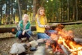 Cute young sisters roasting hotdogs on sticks at bonfire. Children having fun at camp fire. Camping with kids in fall forest Royalty Free Stock Photo