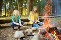 Cute young sisters roasting hotdogs on sticks at bonfire. Children having fun at camp fire. Camping with kids in fall forest Royalty Free Stock Photo