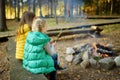 Cute young sisters roasting hotdogs on sticks at bonfire. Children having fun at camp fire. Camping with kids in fall forest Royalty Free Stock Photo