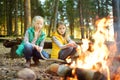 Cute young sisters roasting hotdogs on sticks at bonfire. Children having fun at camp fire. Camping with kids in fall forest Royalty Free Stock Photo