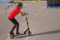 Cute young sportive girl riding on a cick scooter in skatepark