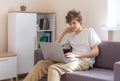 Cute young teenager with laptop on the couch at home. Boy makes homework with a computer. Distance, online education Royalty Free Stock Photo