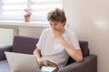 Cute young teenager with laptop on the couch at home. Boy makes homework with a computer. Distance, online education Royalty Free Stock Photo