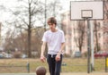 Cute young teenager in white t shirt with a ball plays bask.etball. Sports, hobby, active lifestyle for boys Royalty Free Stock Photo