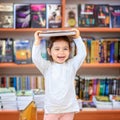 Cute Young Toddler Standing and Holding Book in Head. Child in a Library, Shop,Bookstore. Royalty Free Stock Photo