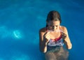 Cute young well tanned girl in the swimming pool holding her diving mask. Copy space.