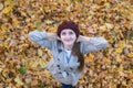 Cute young woman in beret on yellow autumn leaves background. Top view Royalty Free Stock Photo