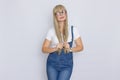 Cute young woman blonde with long hair in a denim jumpsuit and glasses. The girl has a white watch on her hand. She posing over Royalty Free Stock Photo