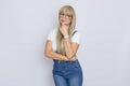 Cute young woman blonde with long hair in a denim jumpsuit and glasses. The girl has a white watch on her hand. She posing over Royalty Free Stock Photo