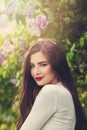 Cute young woman in blossom lilac flowers park