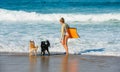 Cute young woman bodyboarding in swimsuit with her dogs
