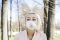 Cute young woman with bubble chewing gum outdoors