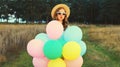 Cute young woman with bunch of colorful balloons outdoors in field Royalty Free Stock Photo