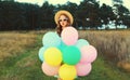 Cute young woman with bunch of colorful balloons outdoors in field Royalty Free Stock Photo