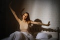 Cute young woman with closed eyes stretches in bed, spreads her arms to the sides Royalty Free Stock Photo