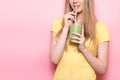 Cute young woman drinking a green gluten-free organic smoothie with straw.