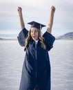 Cute Young woman in her graduation cap and gown showing excitement after graduating