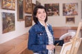 Cute young woman painting a picture near an easel in a studio Royalty Free Stock Photo