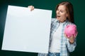 A cute young woman in a plaid shirt talks about financial literacy while holding a piggy bank in her hand Royalty Free Stock Photo