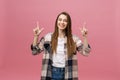 Cute young woman points a finger away isolate over pink background. Copy Space. Royalty Free Stock Photo