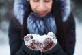 Cute young woman portrait holding snow in her hands wearing warm mittens