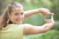 cute young woman puts fingers together framing photograph