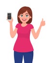 Attractive young woman showing smartphone and thumbs up sign Royalty Free Stock Photo