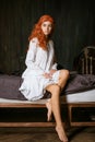 Cute young woman sitting on the edge of the bed in a nightgown Royalty Free Stock Photo