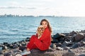 Cute young woman sitting together with american cocker spaniel dog against background of sea Royalty Free Stock Photo