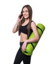 Cute young woman in sportswear with green mat ready for workout. Smiling and talking on the phone. Isolated on white background. Royalty Free Stock Photo