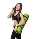 Cute young woman in sportswear with green mat ready for workout. Smiling and talking on the phone. Isolated on white background. Royalty Free Stock Photo