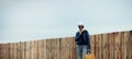 Cute young woman standing near a long wooden fence Royalty Free Stock Photo