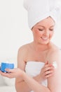 Cute young woman wearing a towel using skin cream Royalty Free Stock Photo