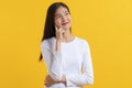 Cute young woman in white casual shirt looking up and thinking / imagination isolated on yellow background in studio Royalty Free Stock Photo