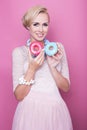 Cute young women hold colorful donuts. Soft colors