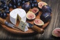 Cuted blue cheese, fresh fig halfs and grapes on rustic wooden plate. Moody scene with selective focus