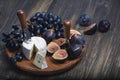 Cuted blue cheese, fresh fig halfs and grapes on rustic wooden plate. Moody scene with selective focus