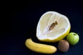 Cuted Pamela fruit, kiwi, ripe banana and green Apple on black background in right corner with copy space