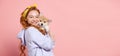 Cheerful redhead young girl with long curly hair holding cute little puppy of corgi dog isolated on pink background