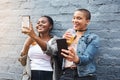 Cuteness overload. two young women standing beside a building smiling and taking selfies while holding their cool drinks