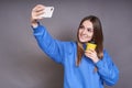 A cutie blonde in a blue hoodie makes a selfie with a yellow cup Royalty Free Stock Photo
