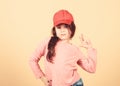 Cutie in cap. Girl cute child wear cap or snapback hat beige background. Little girl wearing bright baseball cap. Modern Royalty Free Stock Photo