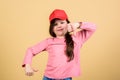 Cutie in cap. Kids fashion. Girl cute child wear cap or snapback hat beige background. Little girl wearing bright
