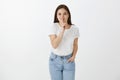 Cutie, it is our secret. Feminine urban female with dark hair in stylish jeans and t-shirt, bending towards camera Royalty Free Stock Photo