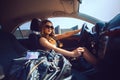 Cutie young girl in sunglasses driving a new car with bag full o