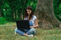 Cutie young girl using a laptop and sits on a grass