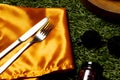 Cutlery, clotch, glasses and jar lying on grass