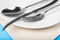Cutlery for food on a blue background. A spoon fork and knife with a white plate, close up Royalty Free Stock Photo
