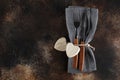 Cutlery on the plate on dark brown background. Fork and table-knife with wooden handles on linen napkin and wooden board